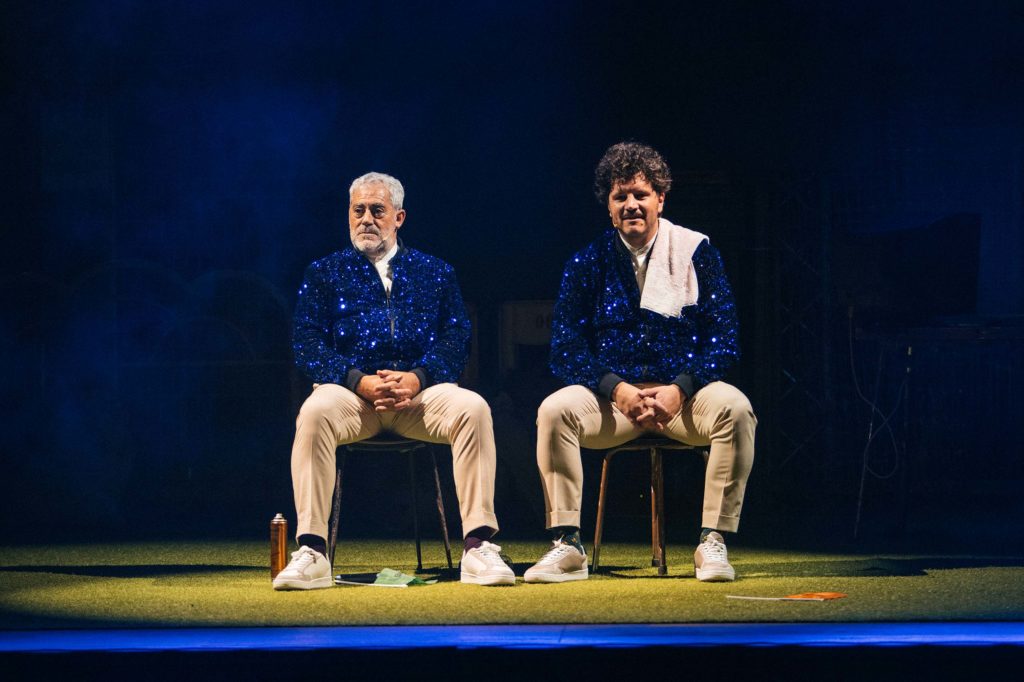 Os actores Carlos Blanco e Xosé A. Touriñá, vestidos iguais, sentados un canda o outro nunha escea do espectáculo Somos Criminais 3